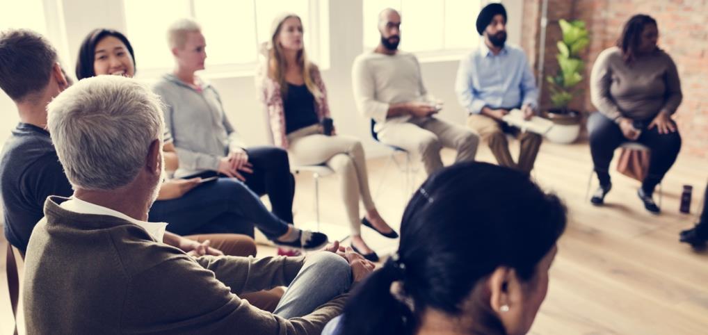 A diverse group of people meet in a round room discussion