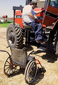 farmer on tractor with wheelchair in foreground