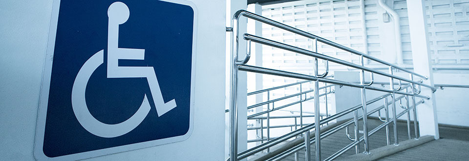 Interior wheelchair ramp with railing. Identified with the international symbol for disability.