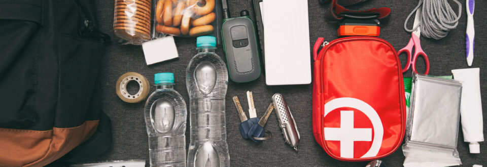 Emergency backpack equipment organized on the table. Documents, water, food, and first aid kit