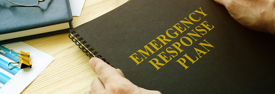 Person holding a spiral-bound document titled Emergency Response Plan