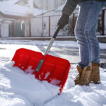 Closeup of someone shoveling snow off a sidewalk
