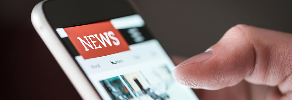 Close up of someone reading a news application on a smartphone.