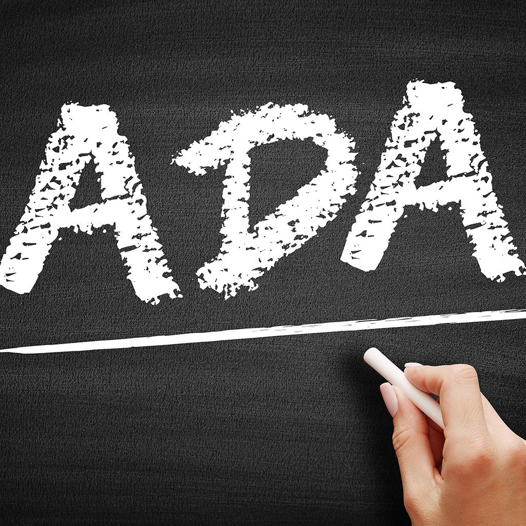 ADA acronym written on a blackboard. Underneath, a hand holds a piece of chalk.