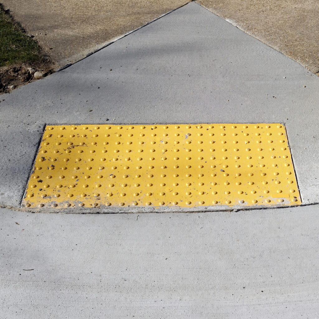 Sidewalk curb ramp with bumpy anti-slip pad