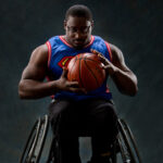 Master Hinkle in his sports wheelchair. He is wearing a Superman basketball jersey and holding a basketball.