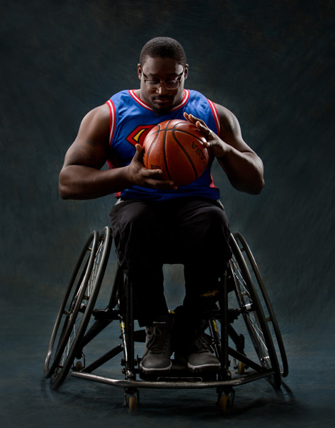 Master Hinkle in his sports wheelchair. He is wearing a Superman basketball jersey and holding a basketball.