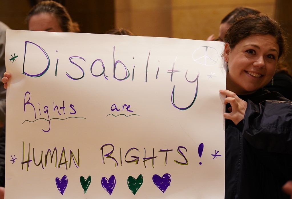 Woman holding a sign that reads, "Disability Rights are HUMAN RIGHTS!"