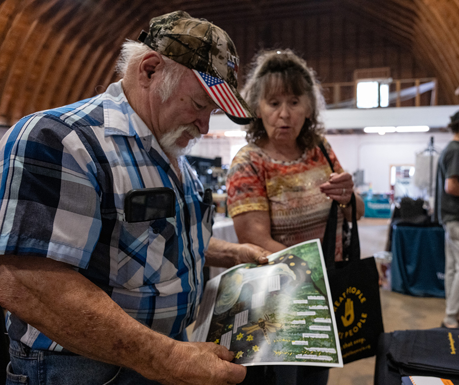 Two visitors to the MCD booth look at an art poster.